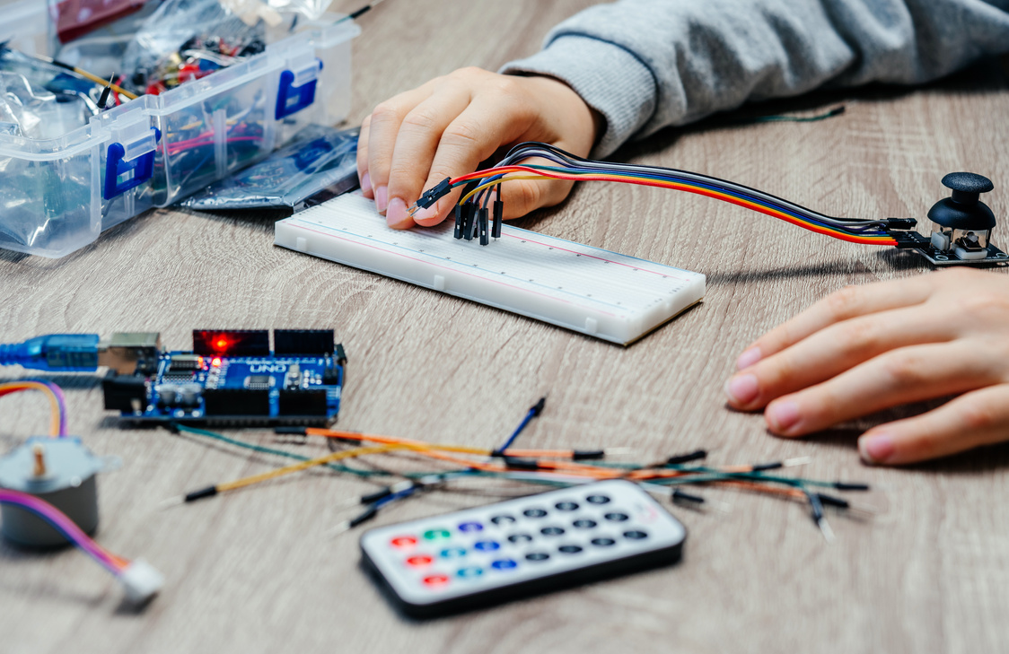 A Child Plugging Cables to Sensor Chips While Learning Arduino Coding and Robotics